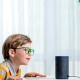 Kleiner Junge steht vor Amazon Echo Lautsprecher